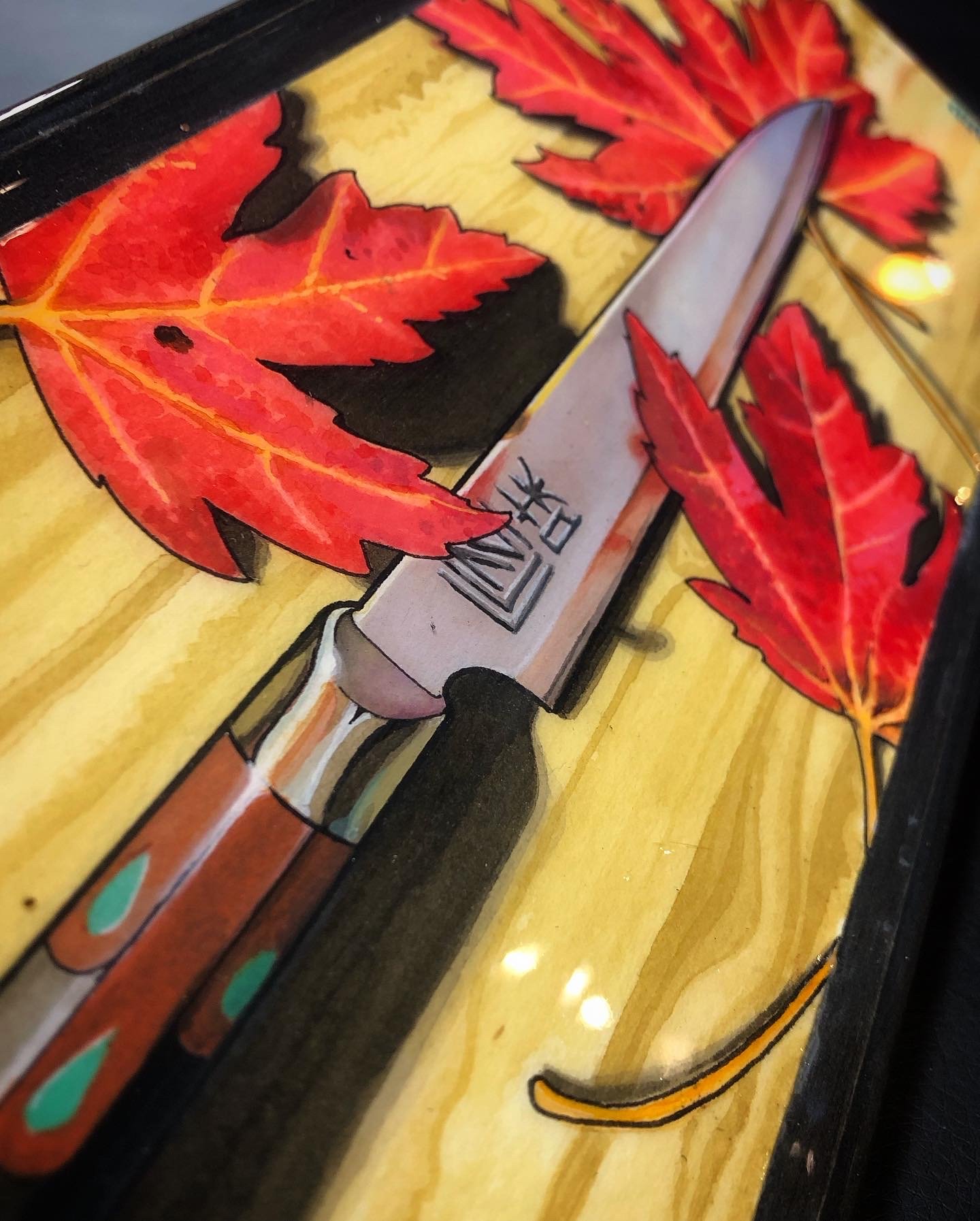 A watercolor painting of a Japanese knife with red and orange maple leaves on a yellow background.