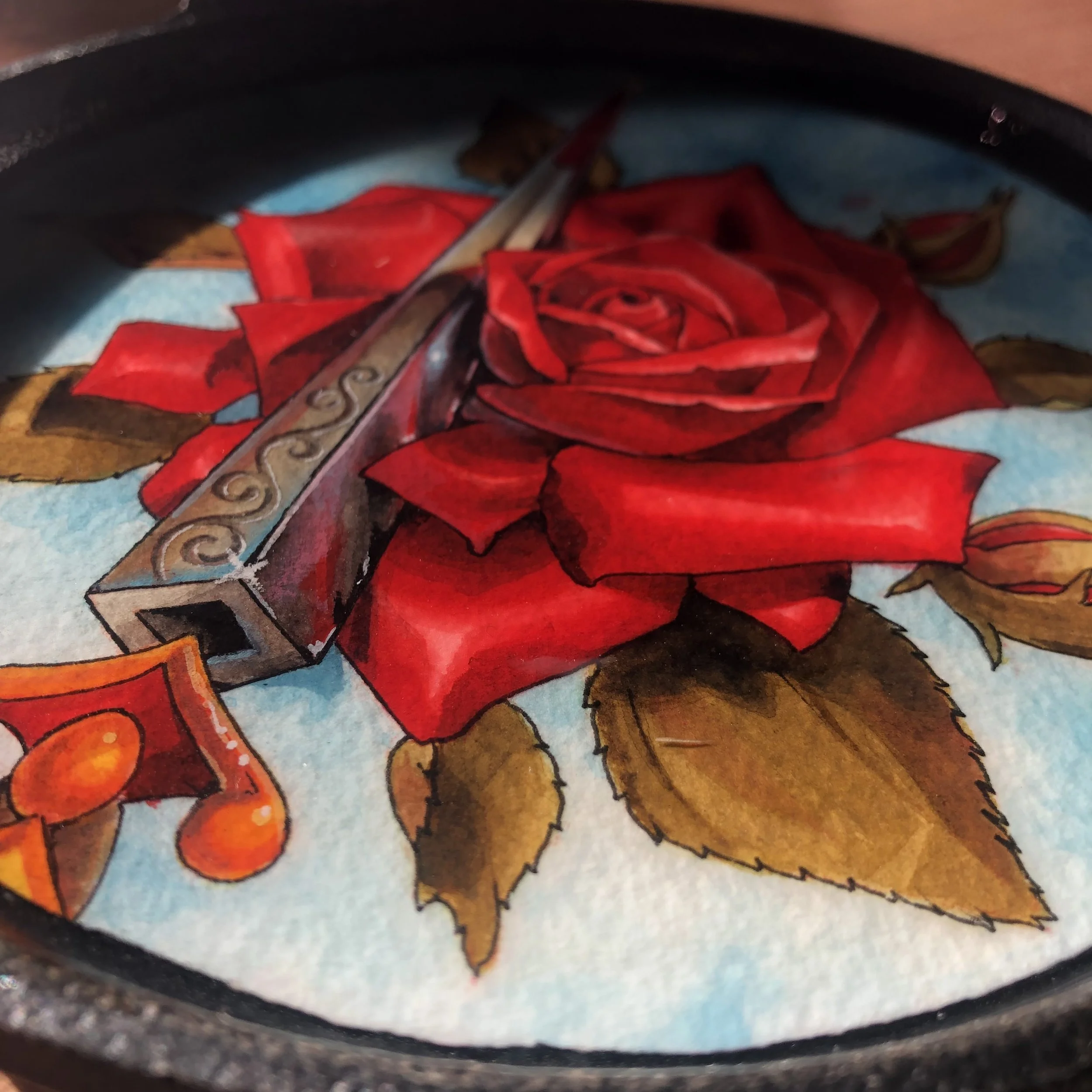 A close-up of a colorful illustration featuring a red rose, a metallic dagger with intricate engravings, a music note, and some brown leaves on a light blue background.