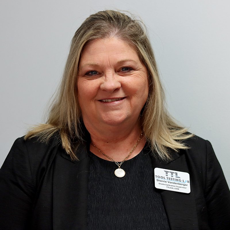 A young woman with dark hair in a messy bun, smiling, wearing a white top, against a plain white background.