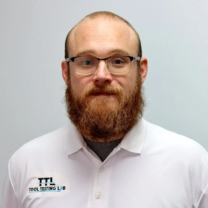 Smiling woman with dark hair styled in a messy bun, wearing a white top, and a nose ring, against a plain light background.