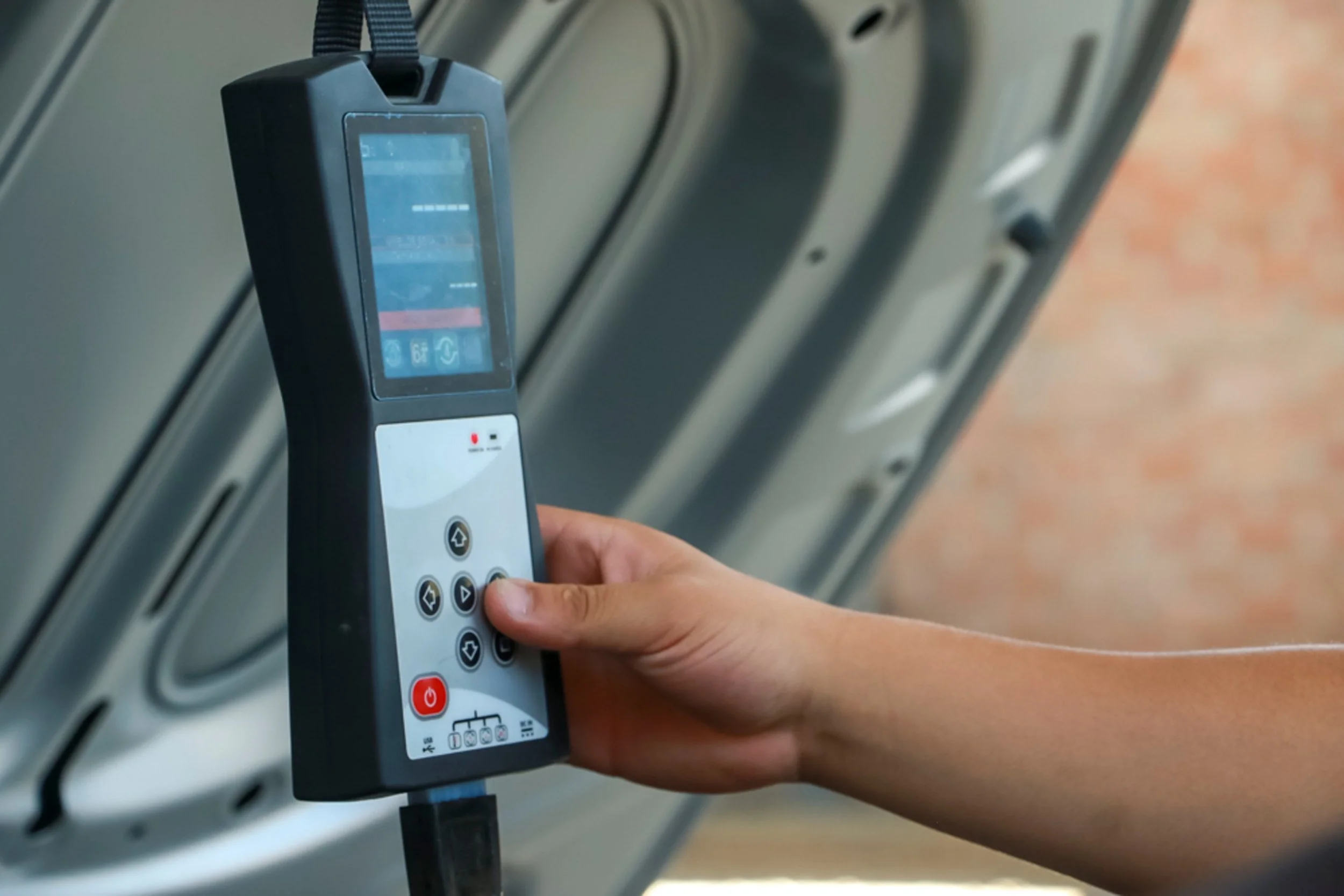 A person holding a control device or remote in front of an overhead door or garage door with a brick wall background.