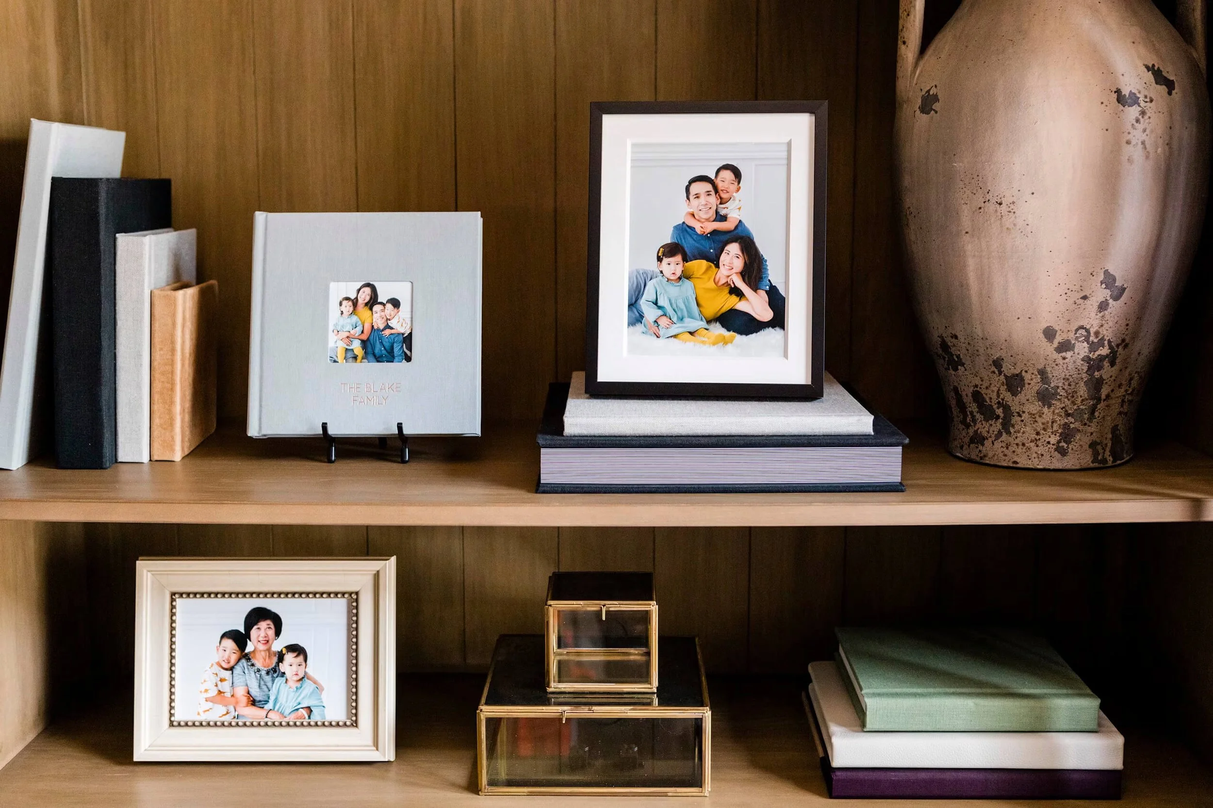 A variety of display items on a shelf including albums, framed desk art, framed 5x7, matted framed print