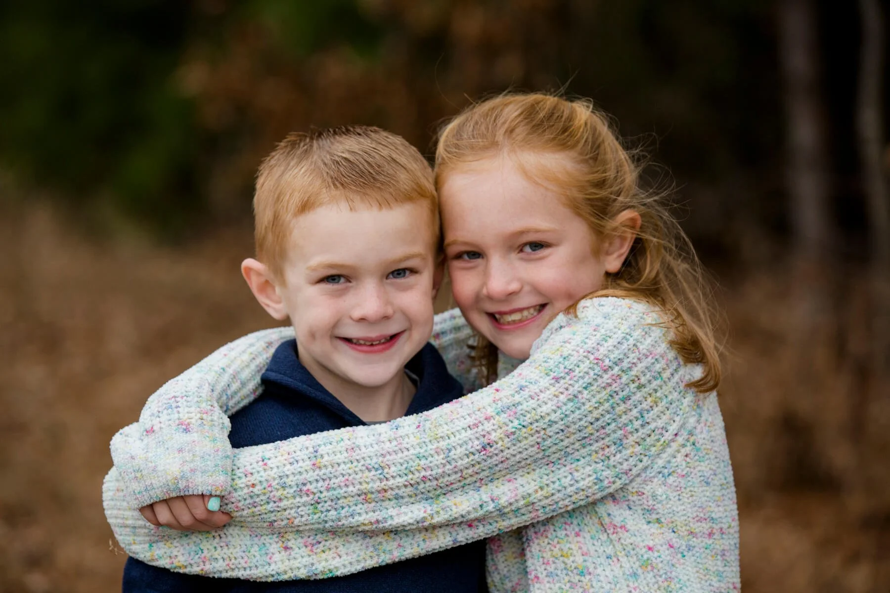Two children who are siblings hugging one another during a family photo session
