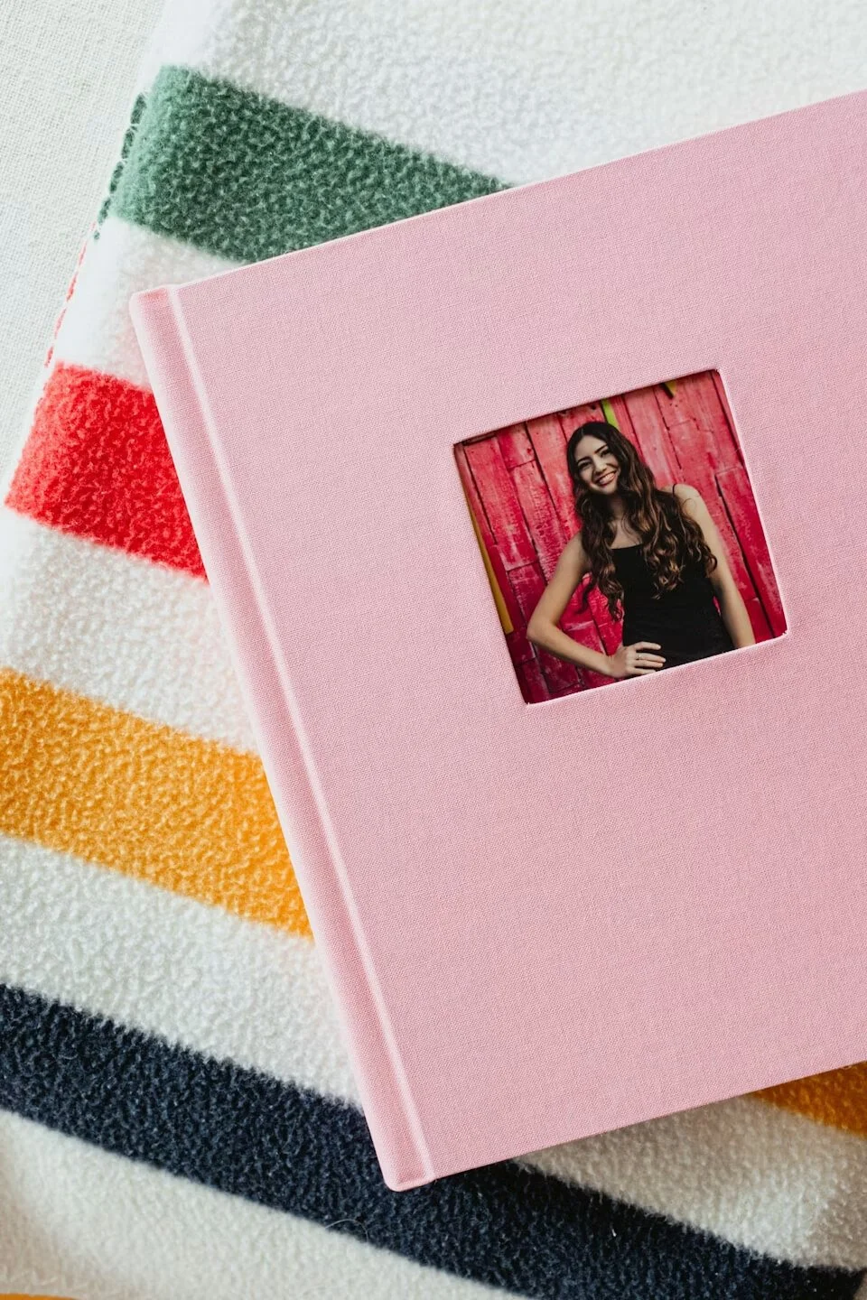 pink linen cover album displayed on a striped blanket