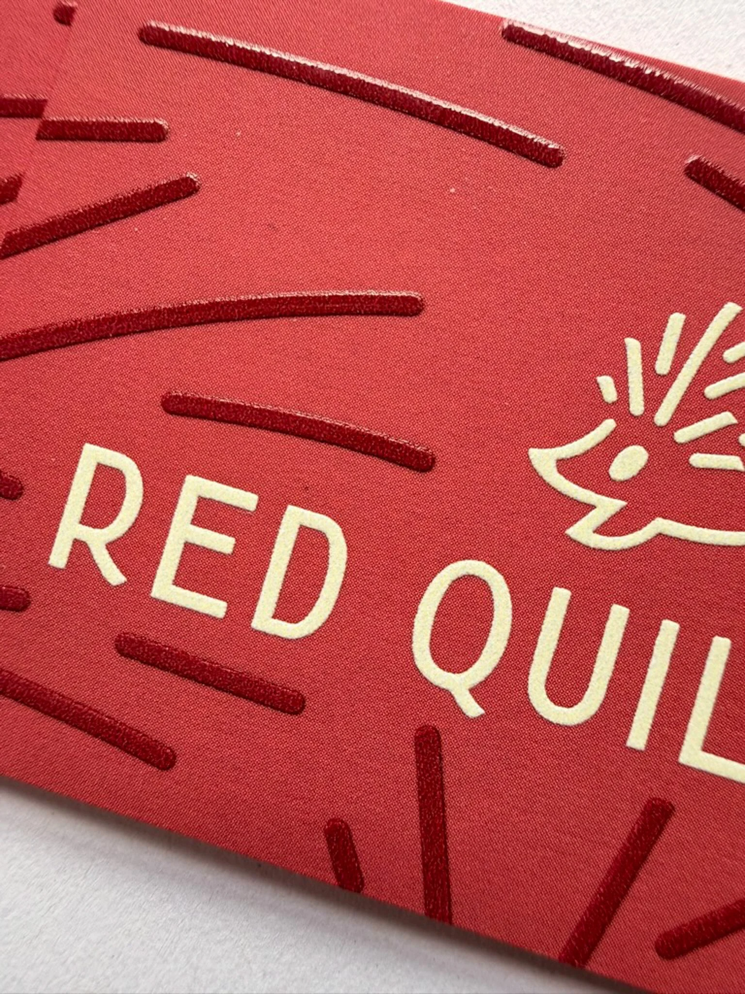Close-up of a business card for Red Quill Law with the primary logo of a hedgehog and type with a custom quill pattern embossed in the background.