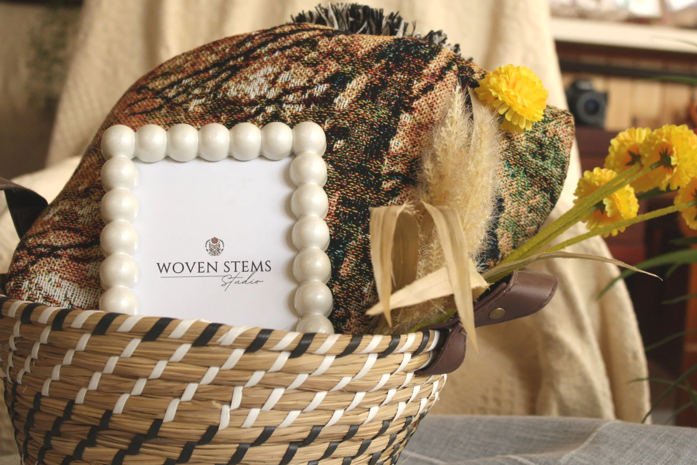Two embroidered pillows with floral and bird designs and the initials 'WSS' embroidered in red, resting in a navy and green plaid bag near a fireplace.