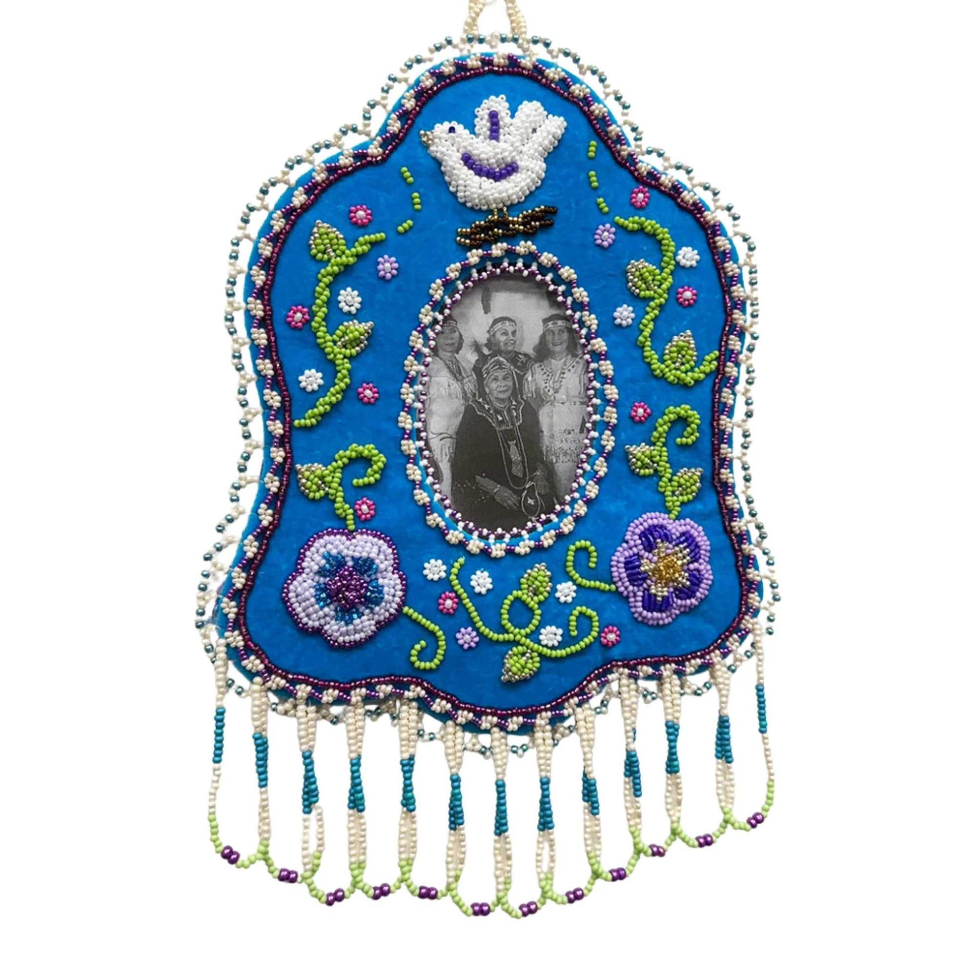 Beaded religious shrine with a black and white photo of people in traditional clothing, surrounded by colorful embroidery and beadwork, featuring a dove symbol at the top.