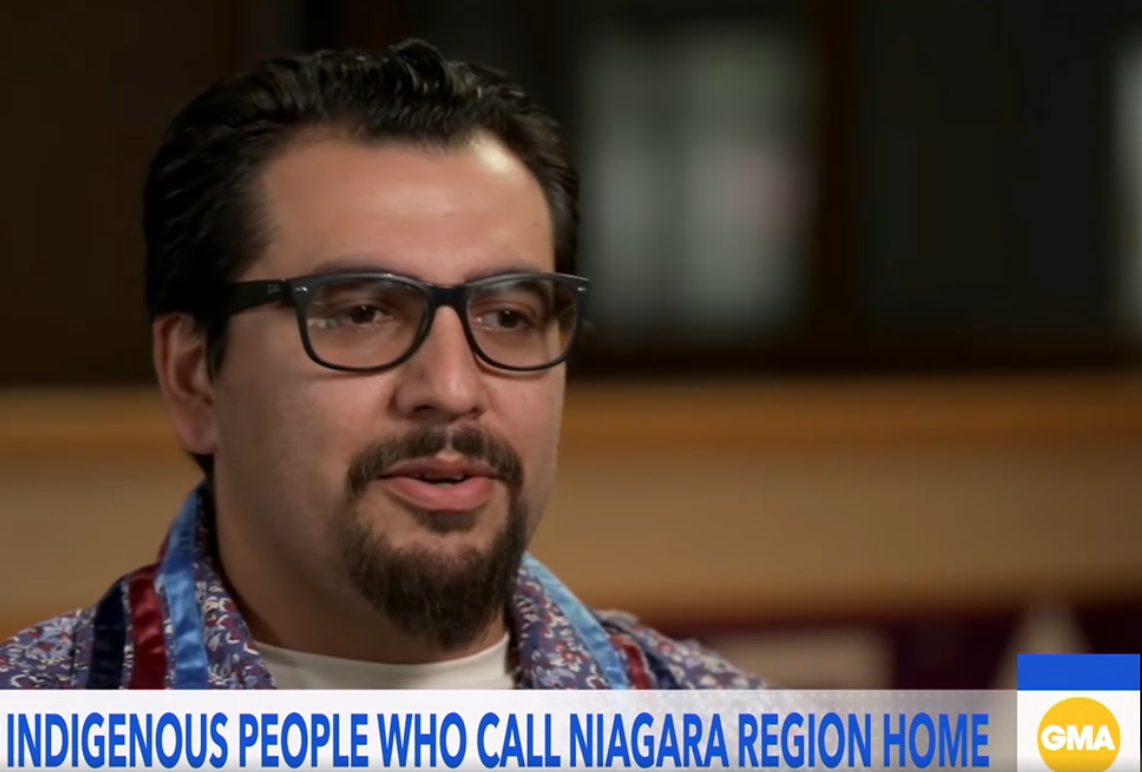 Man with glasses and a beard speaking during an interview, with a news banner at the bottom reading 'Indigenous People Who Call Niagara Region Home' on ABC's Good Morning America.