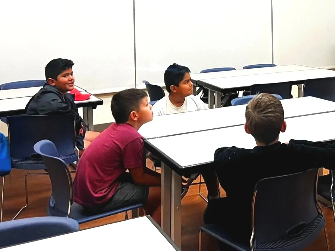 A group of children working on a robotics project with an instructor in a classroom.