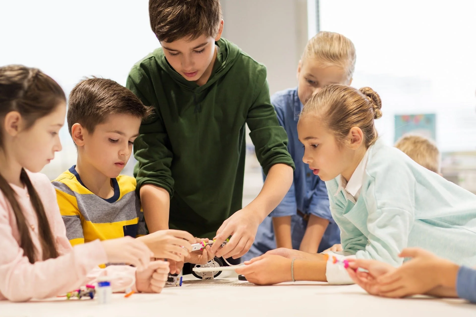 A group of children working on a robotics project with an instructor in a classroom.