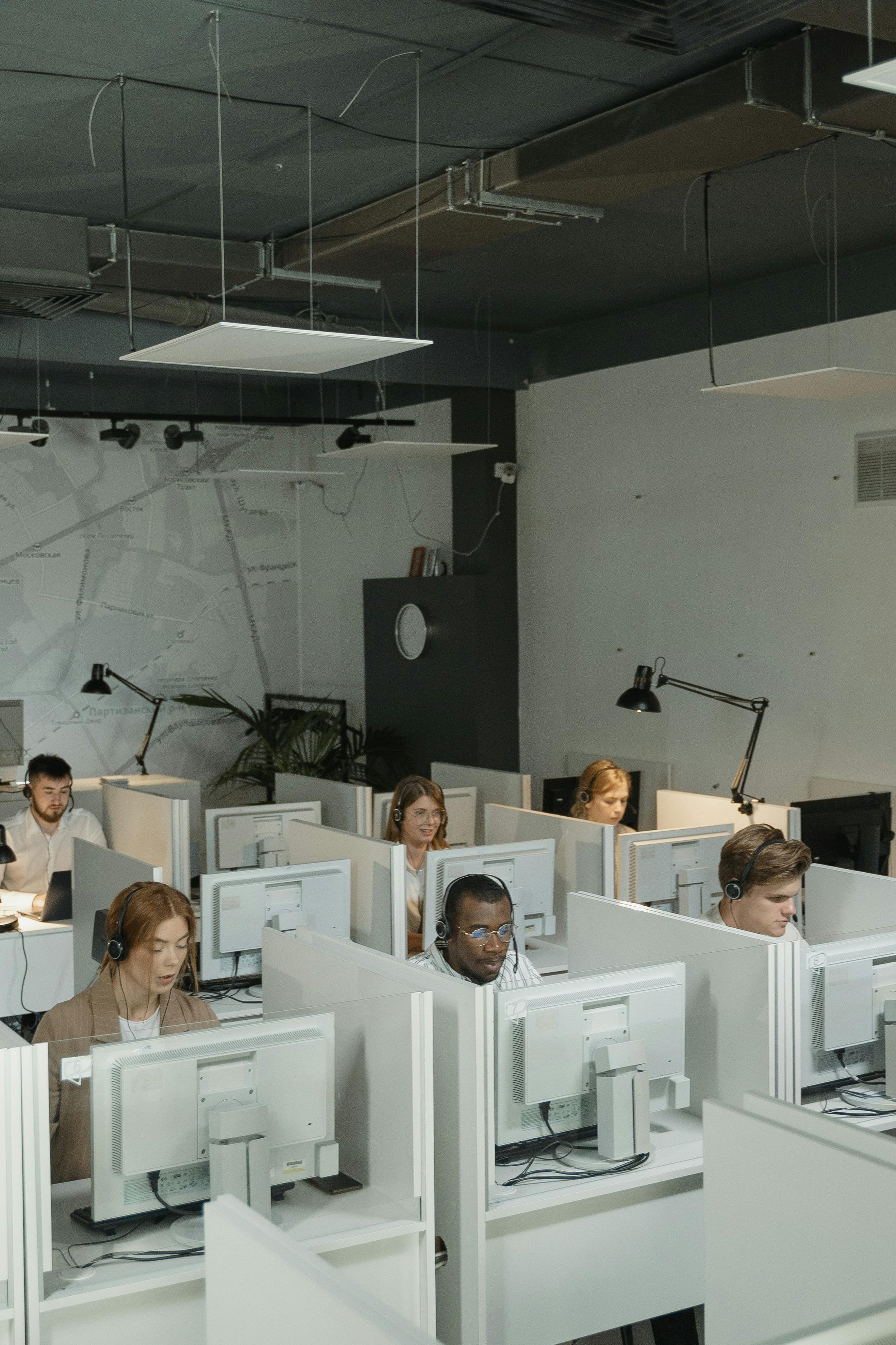 Employees working at cubicles with computers in an office.