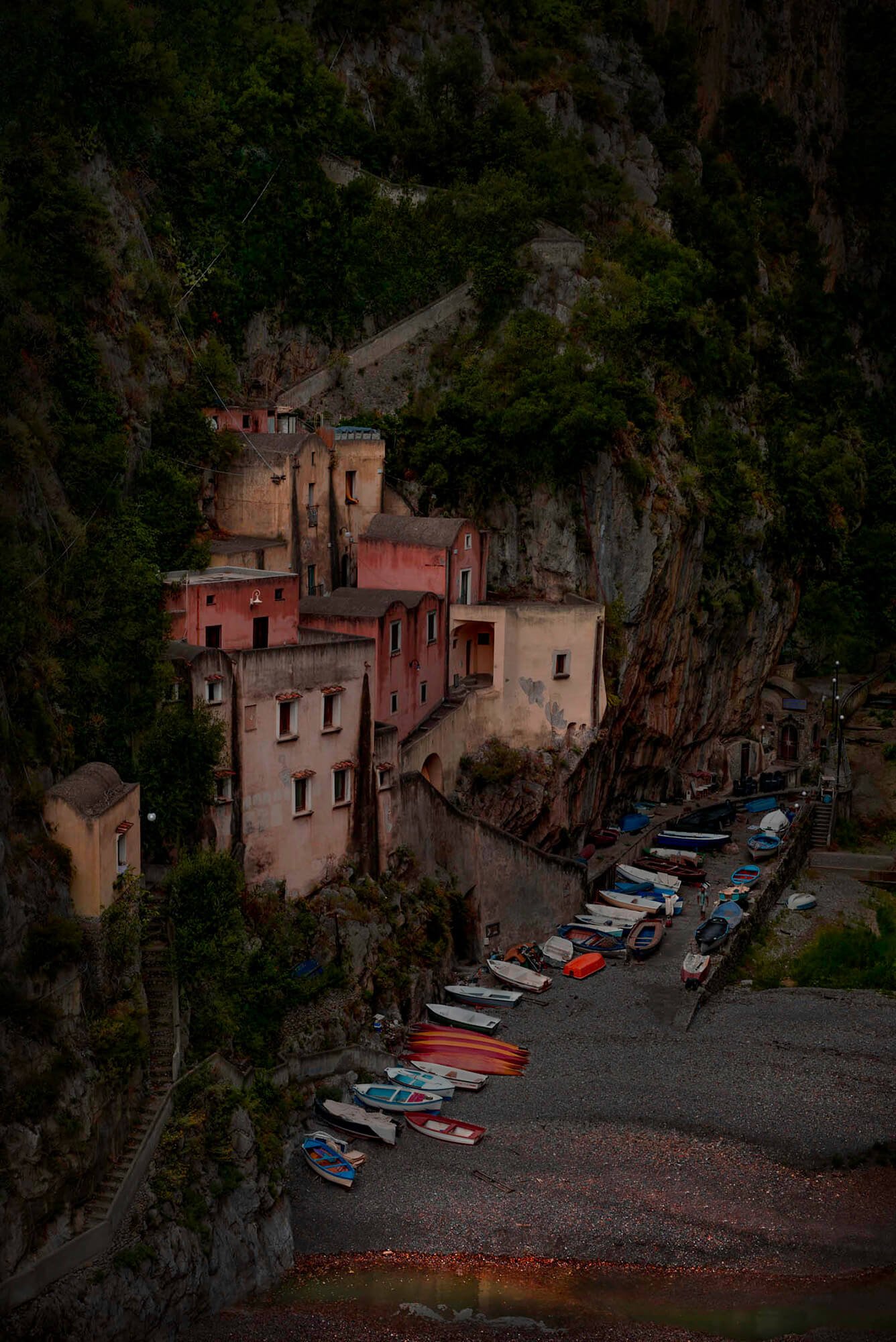 Colorful buildings built into a steep hillside overlooking a small boat-filled harbor.