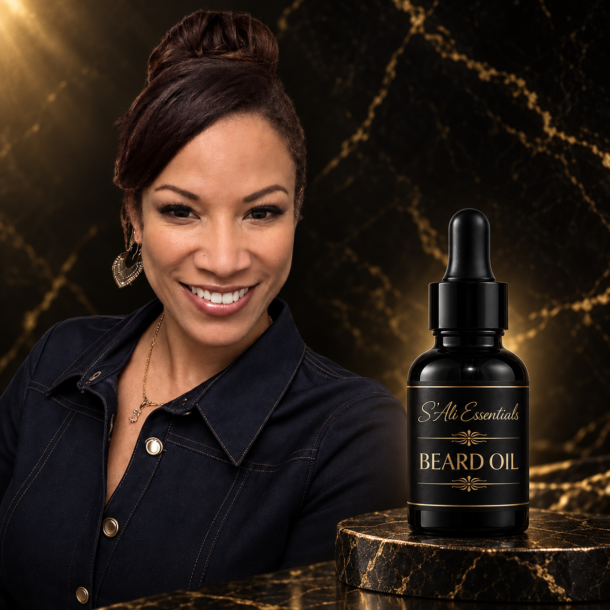 A smiling woman with dark hair in an updo, wearing earrings and a necklace, beside a bottle of beard oil labeled 'S'Ali Essentials' on a black marble surface with gold veining and a dark marbled background.