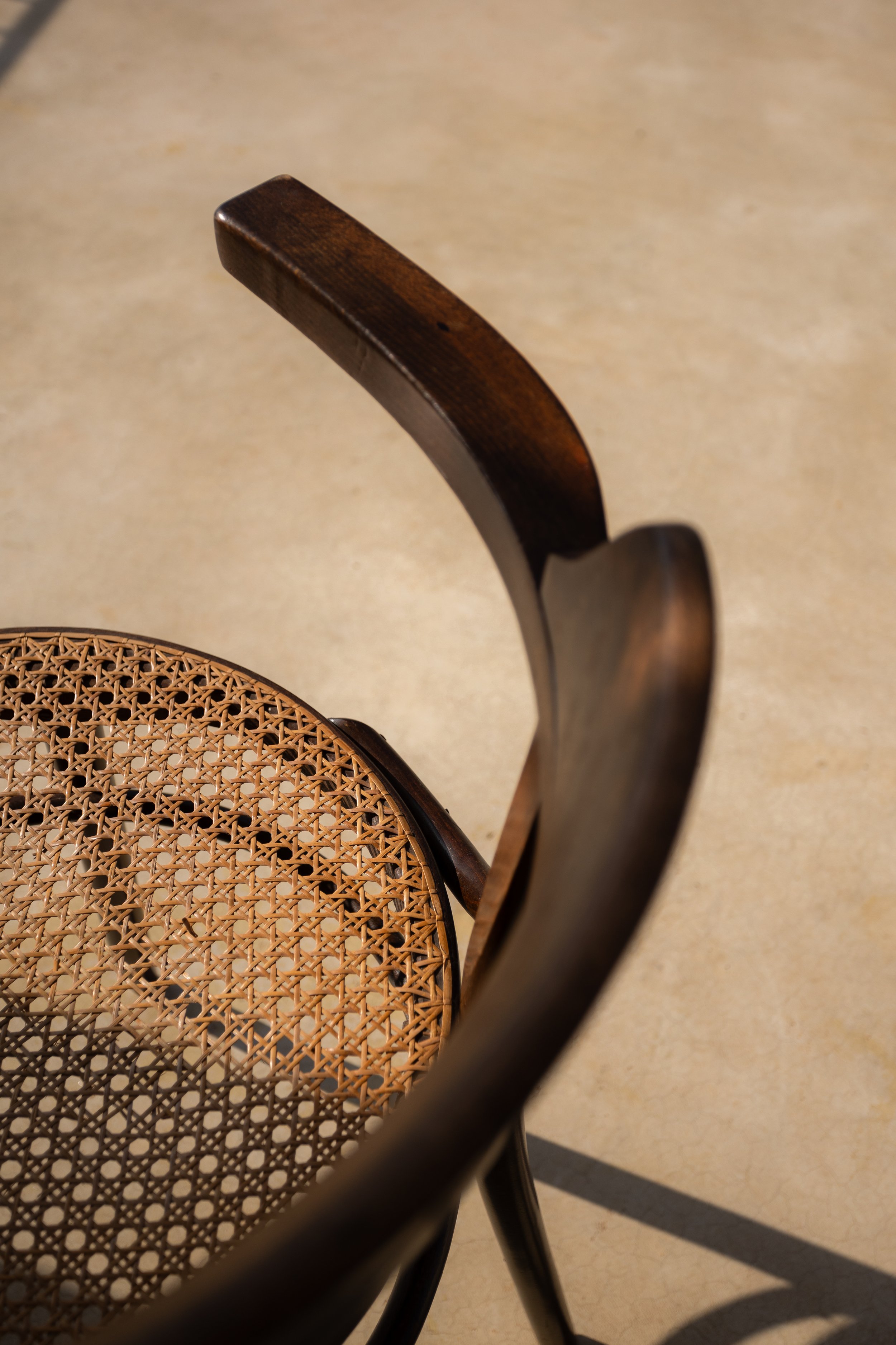 Nahaufnahme eines Holzstuhls mit geflochtenem Sitz, Blick von oben, Schatten auf dem Boden