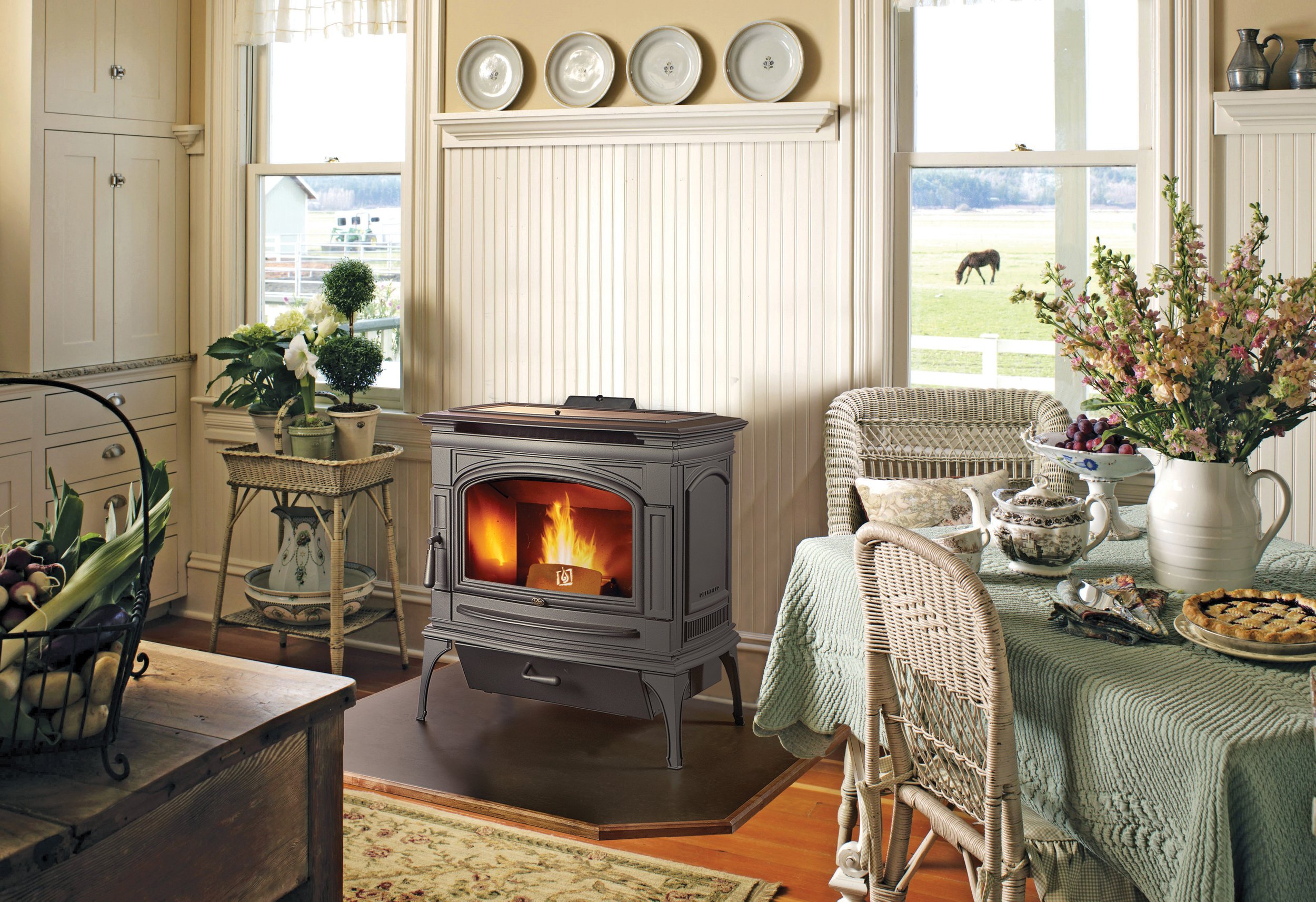 a pellet stove in a cottage-style house with a farm scene in the background