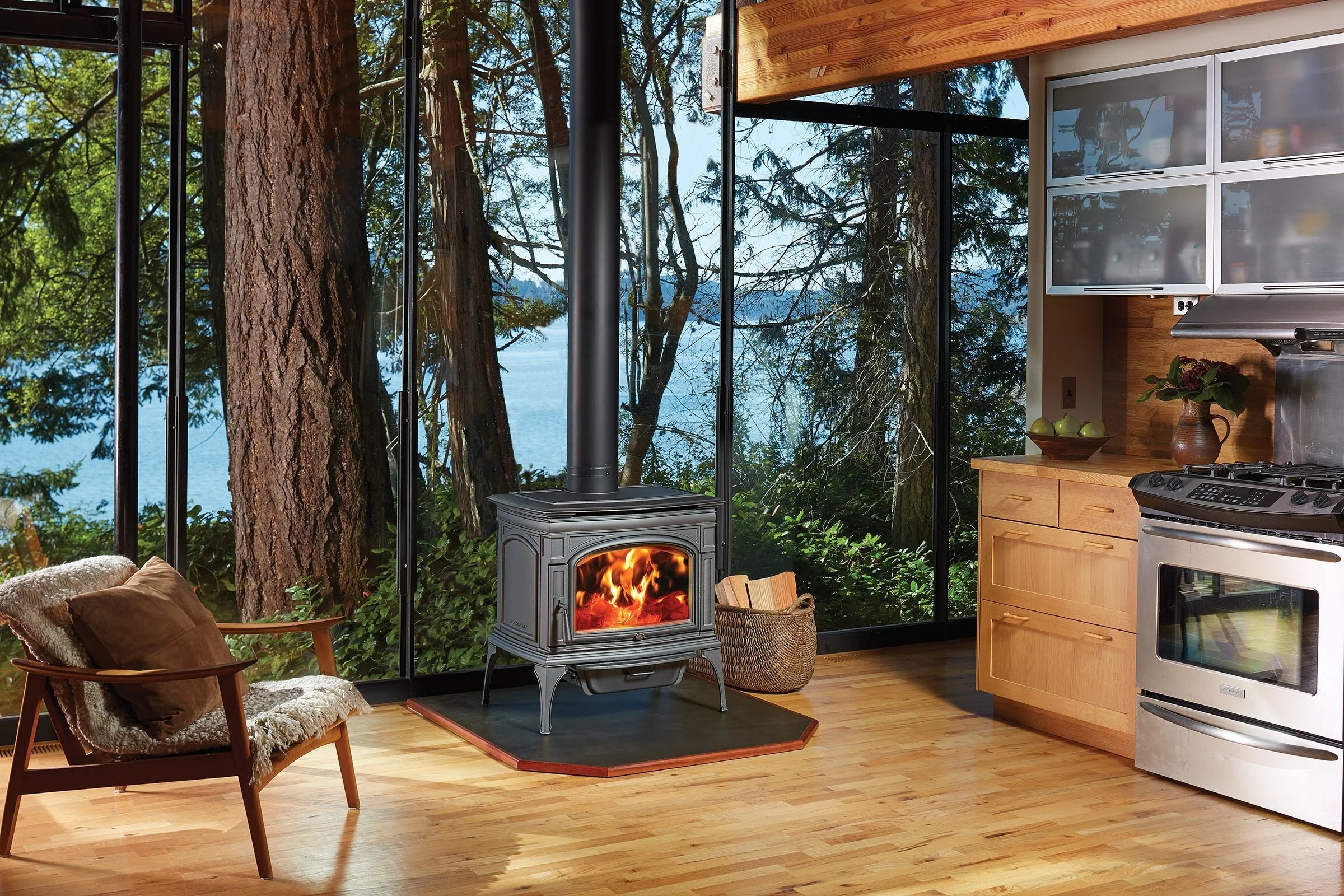 wood stove against glass wall with mountains and water in the distance