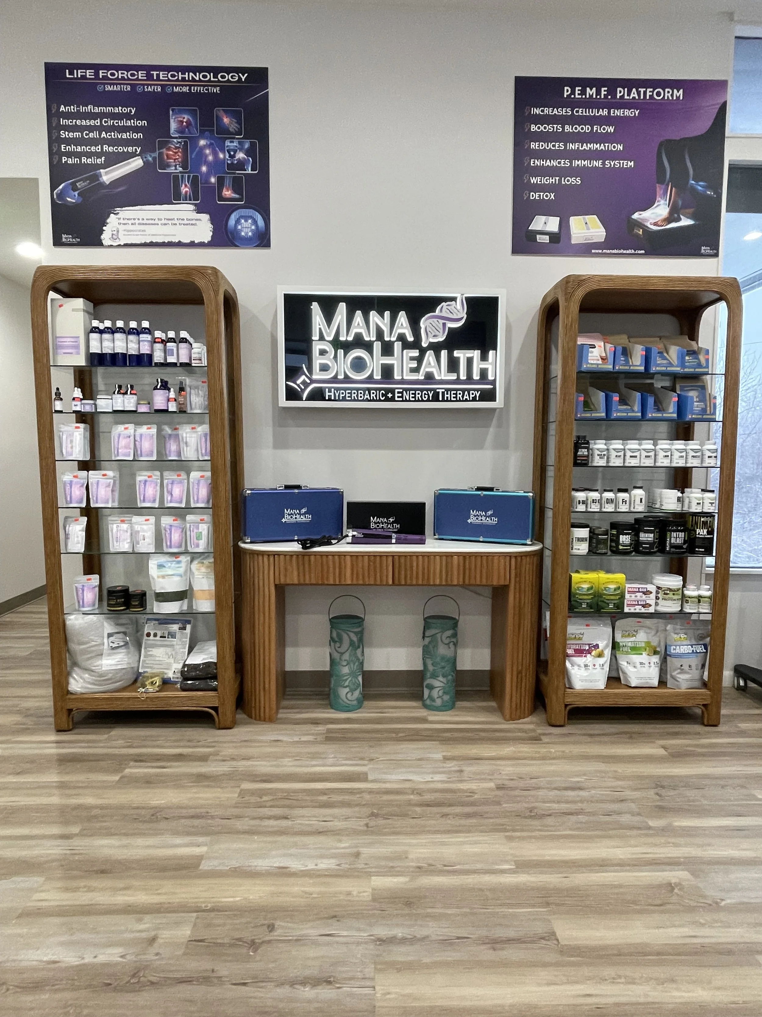 Display shelves with health supplements and products in a wellness center, featuring a centered illuminated sign that reads "MANA BIOHEALTH" with a DNA helix graphic.