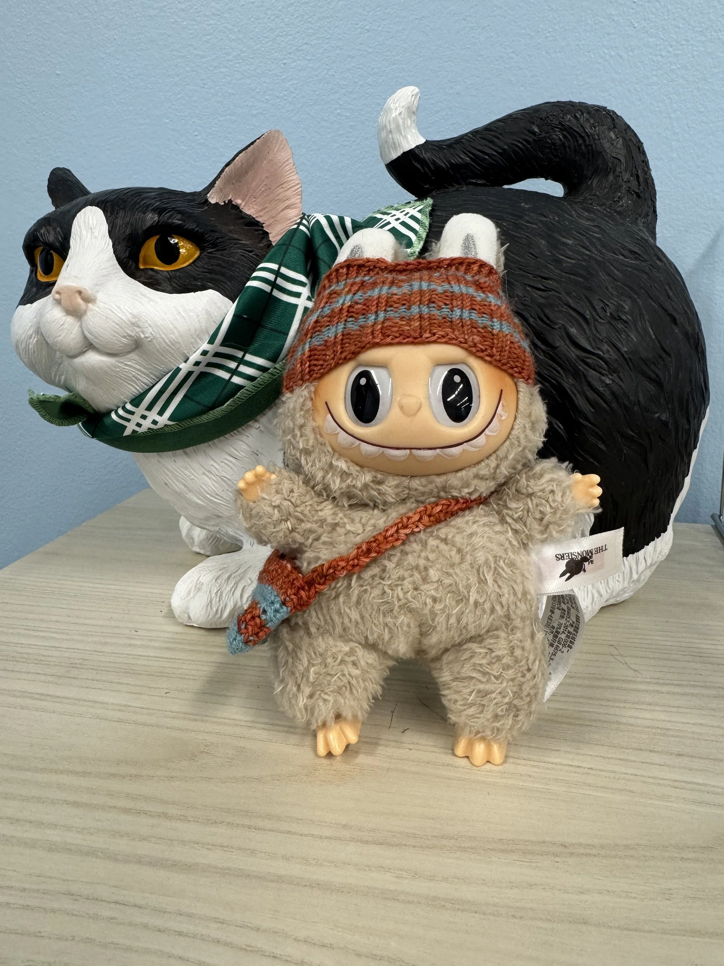 A knit hat and messenger bag for a terrifying creature made as a gag gift for a coworker
