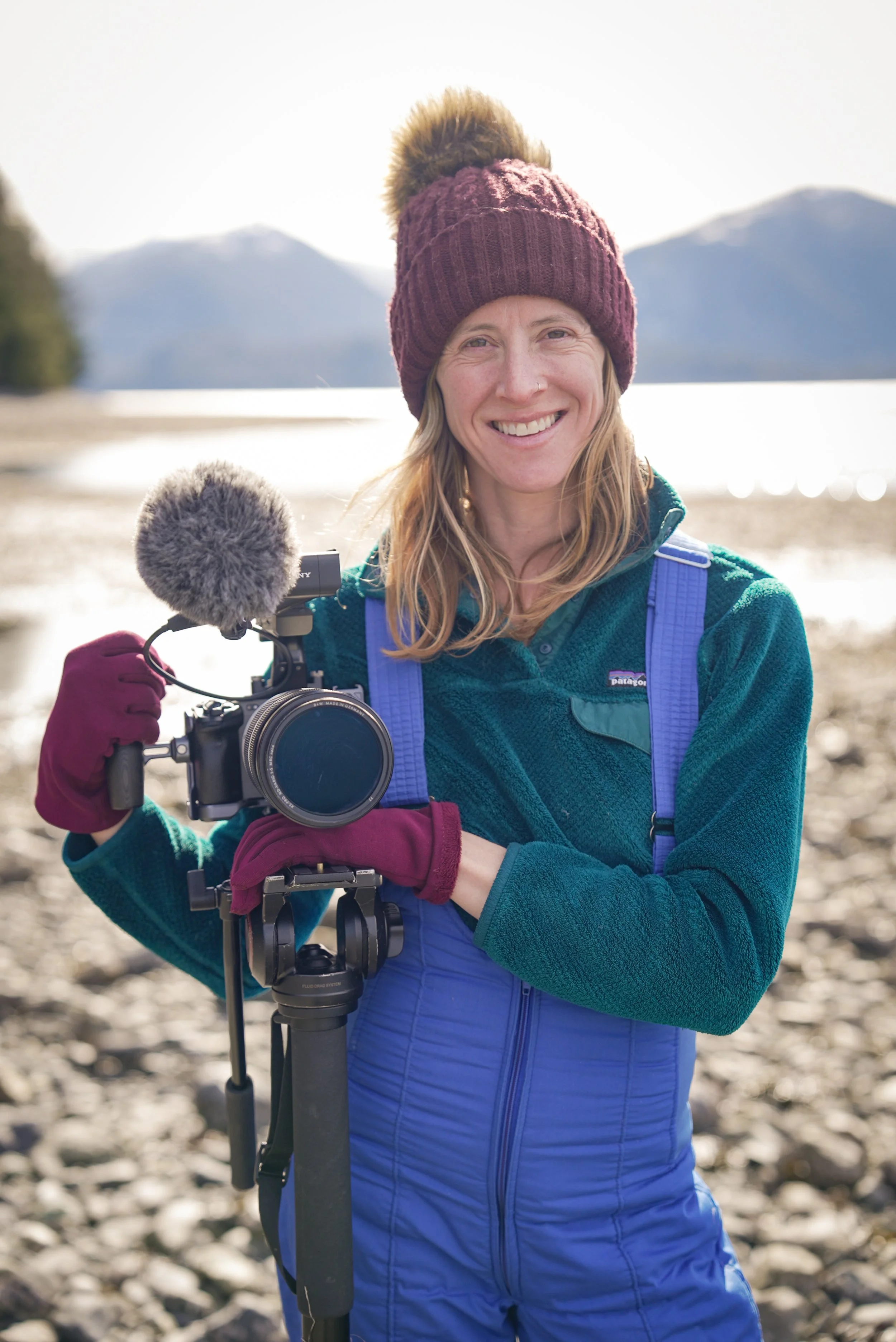 Kika Tuff stands on a beach in Sitka, Alaska with a camera in hand