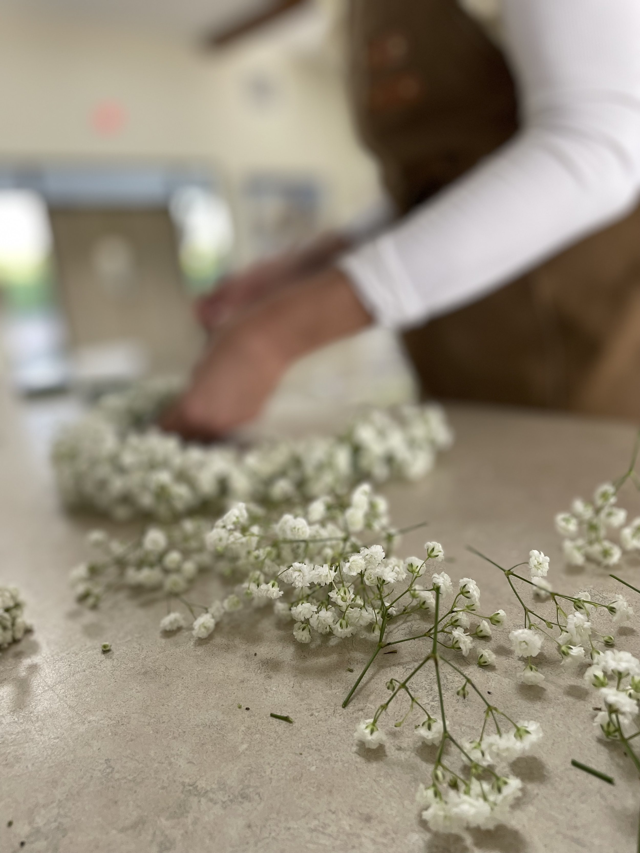 Person arranging white baby's breath flowers on a table.