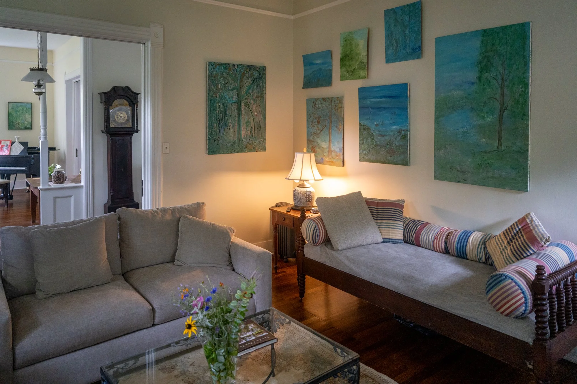 The living room includes a TV, daybed couch, wingback chairs, and a lovely working fireplace for intimate gatherings. The downstairs bathroom is accessible via the pictured door, and the room can be closed off with built-in sliding doors for privacy.