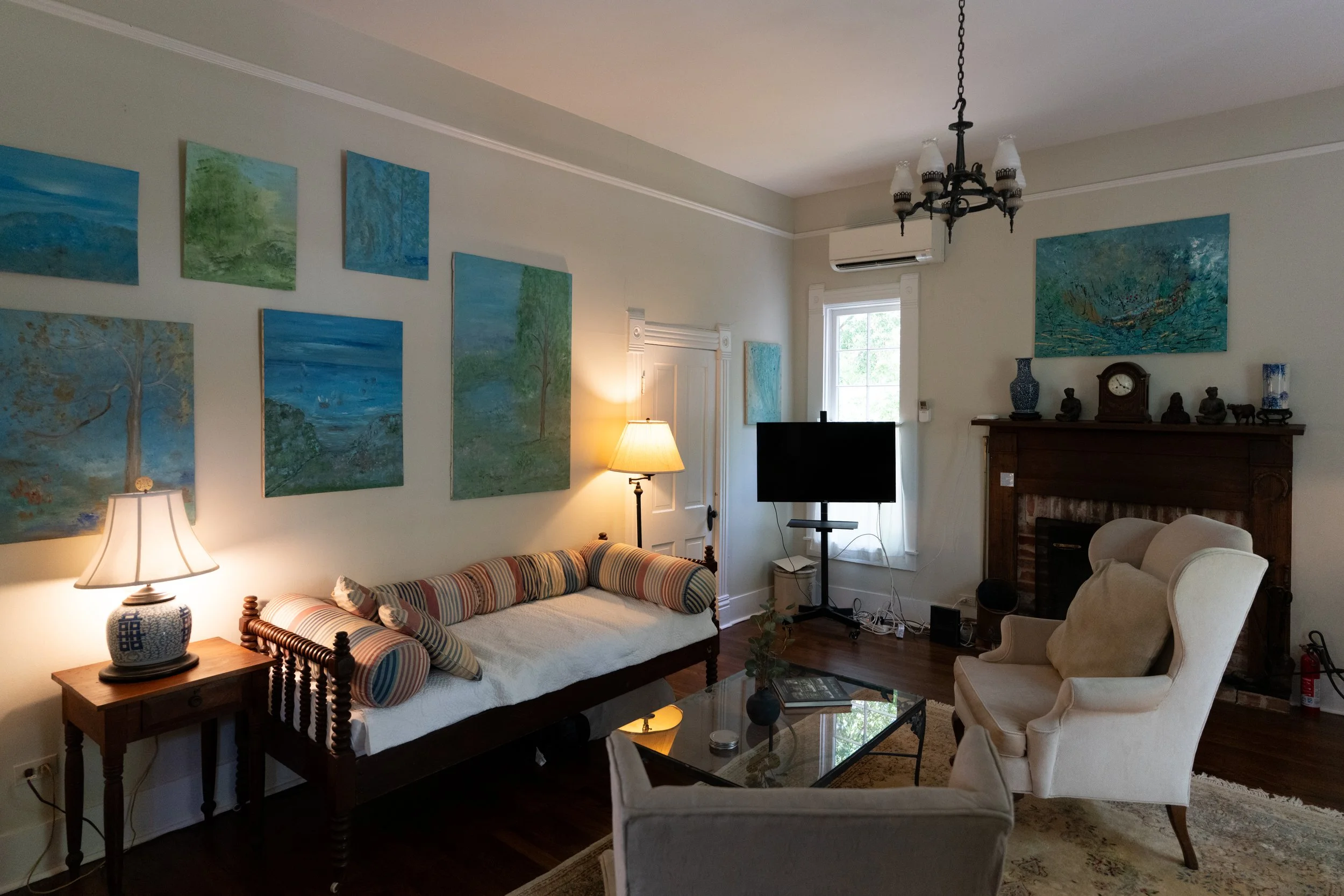 The living room includes TV, daybed couch, wingback chairs, and a lovely working fireplace for intimate gatherings. The downstairs bathroom is accessible from the door pictured, and the room can be closed off with built-in sliding doors for privacy.