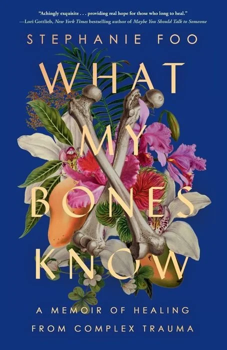 Book cover for 'What My Bones Know' by Stephanie Foo, featuring an illustration of a human skeleton intertwined with colorful flowers and green leaves against a blue background.