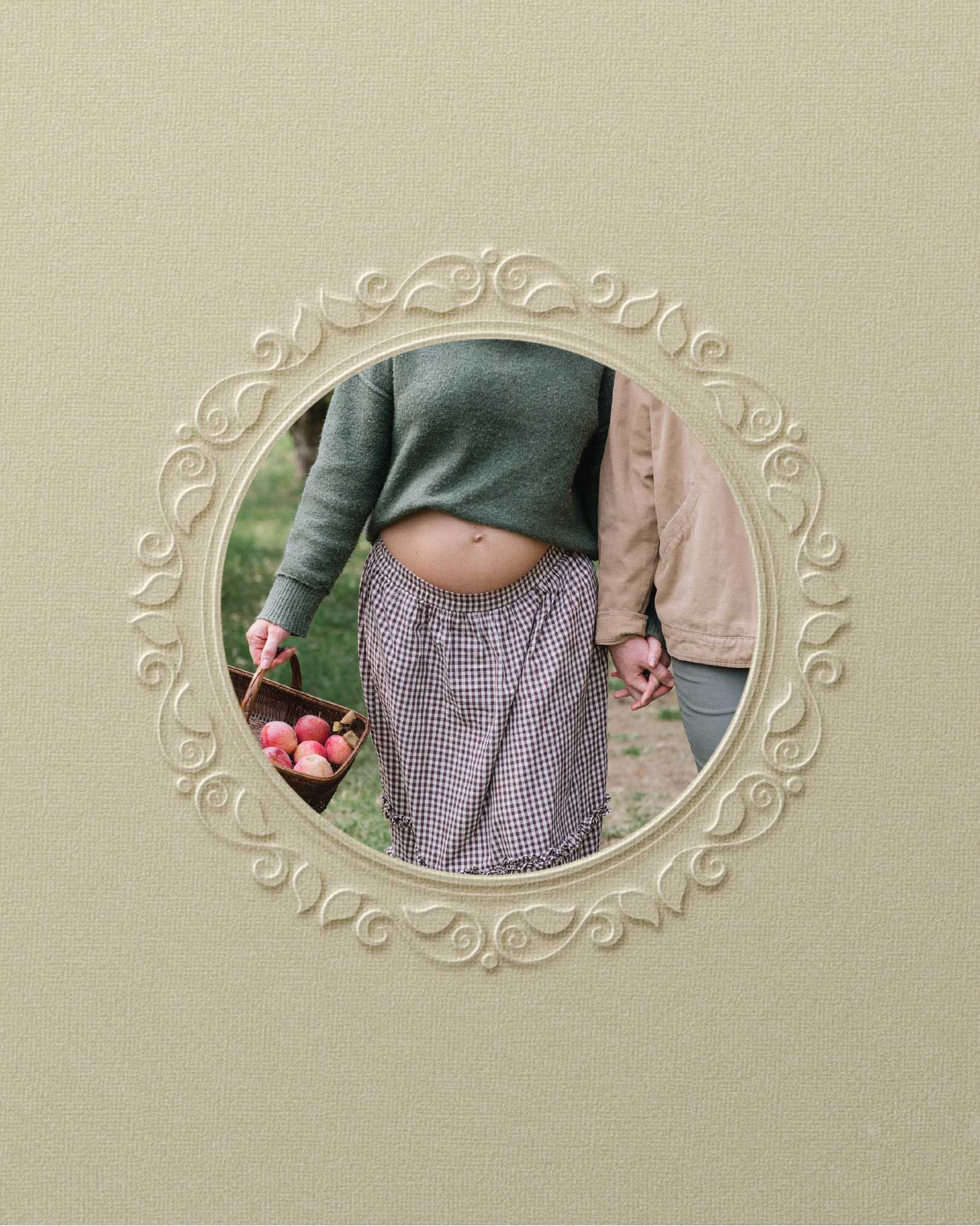 A person holding a basket of red apples while standing outdoors, seen through a decorative oval-shaped mirror frame.