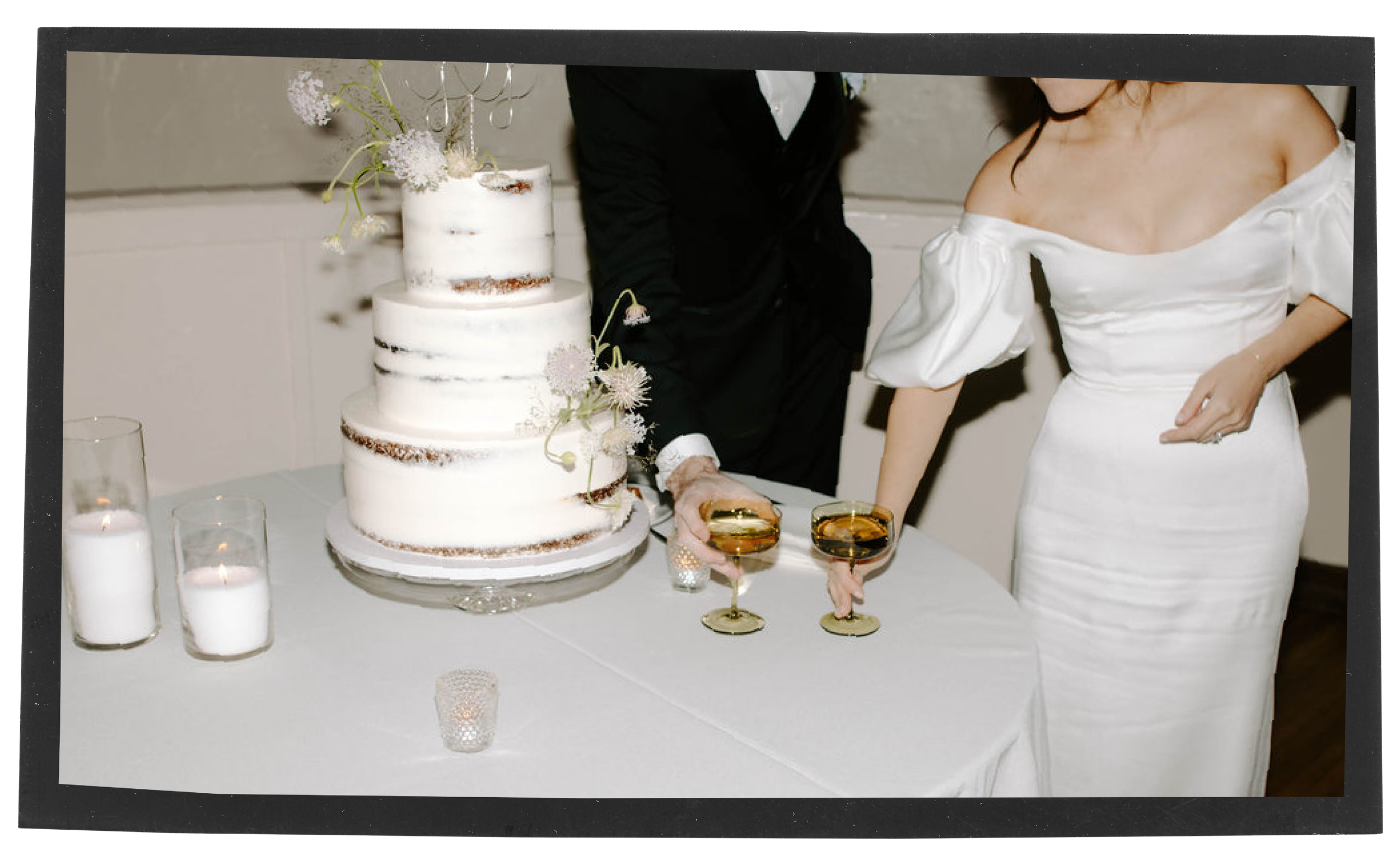 Bride and groom cutting a wedding cake with two glasses of champagne.