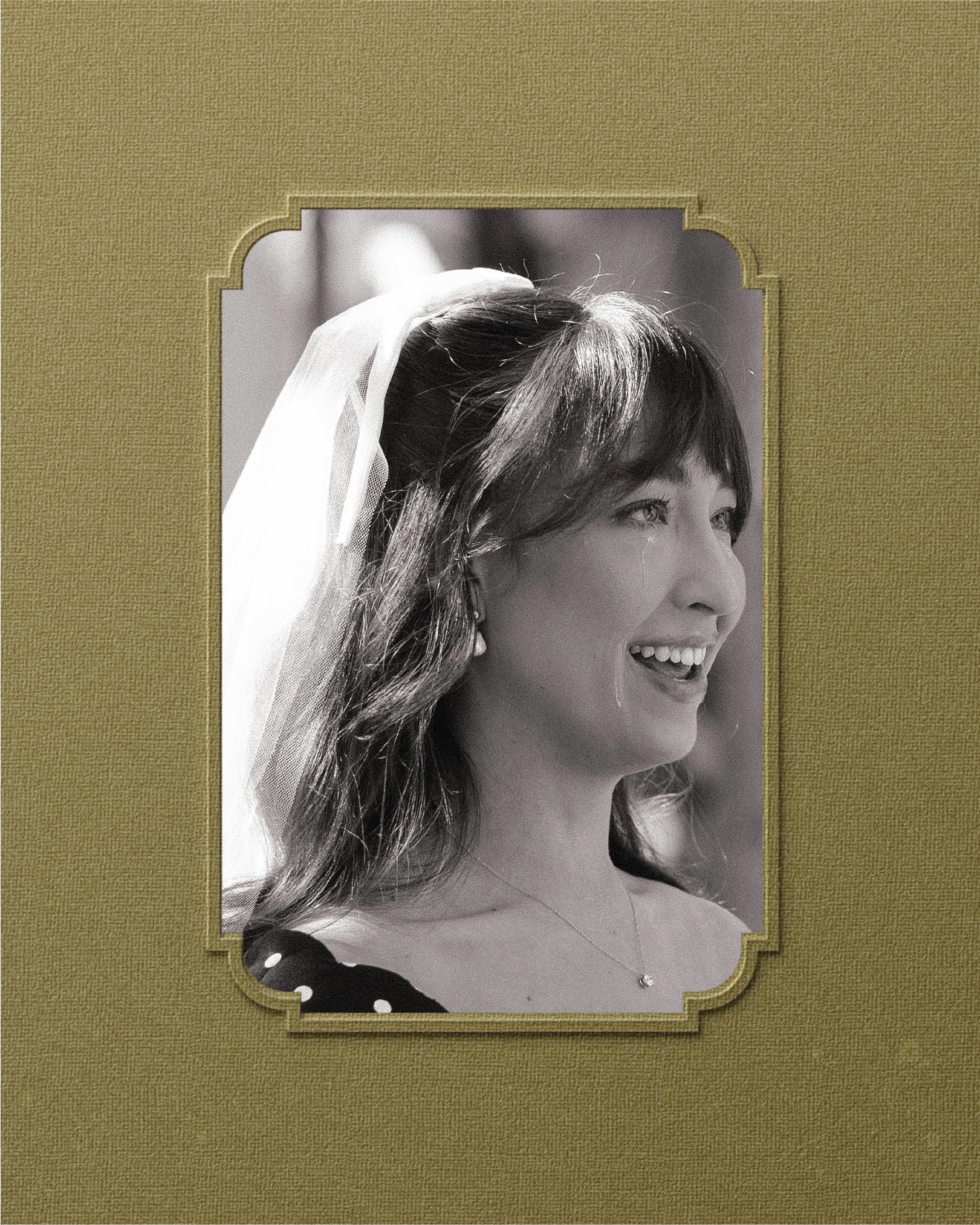 Black and white portrait of a smiling bride with a veil, looking to the side.