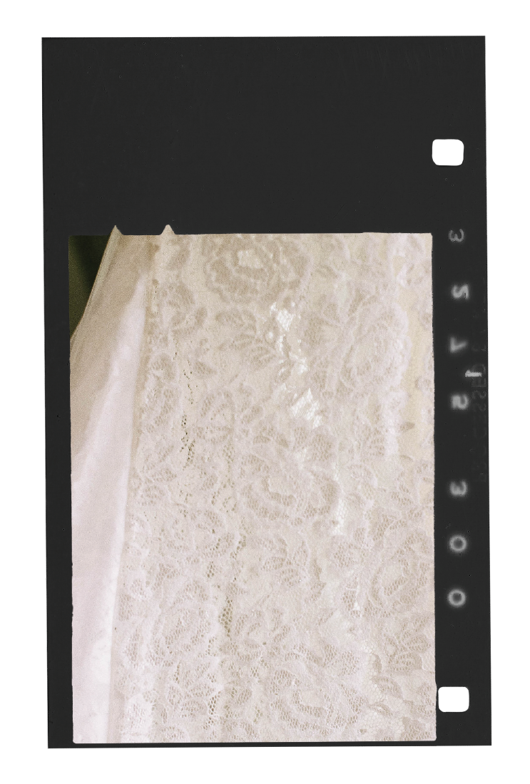 Close-up of a black negative film strip showing a section of white lace fabric.