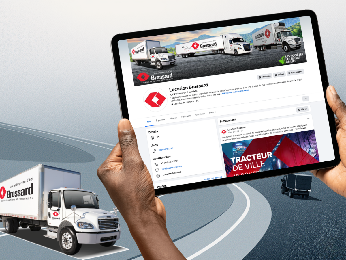 Une personne tient une tablette affichant la page Facebook de Location Brossard, une entreprise de location de camions et remorques, avec deux camions Brossard en arrière-plan sur une route.
