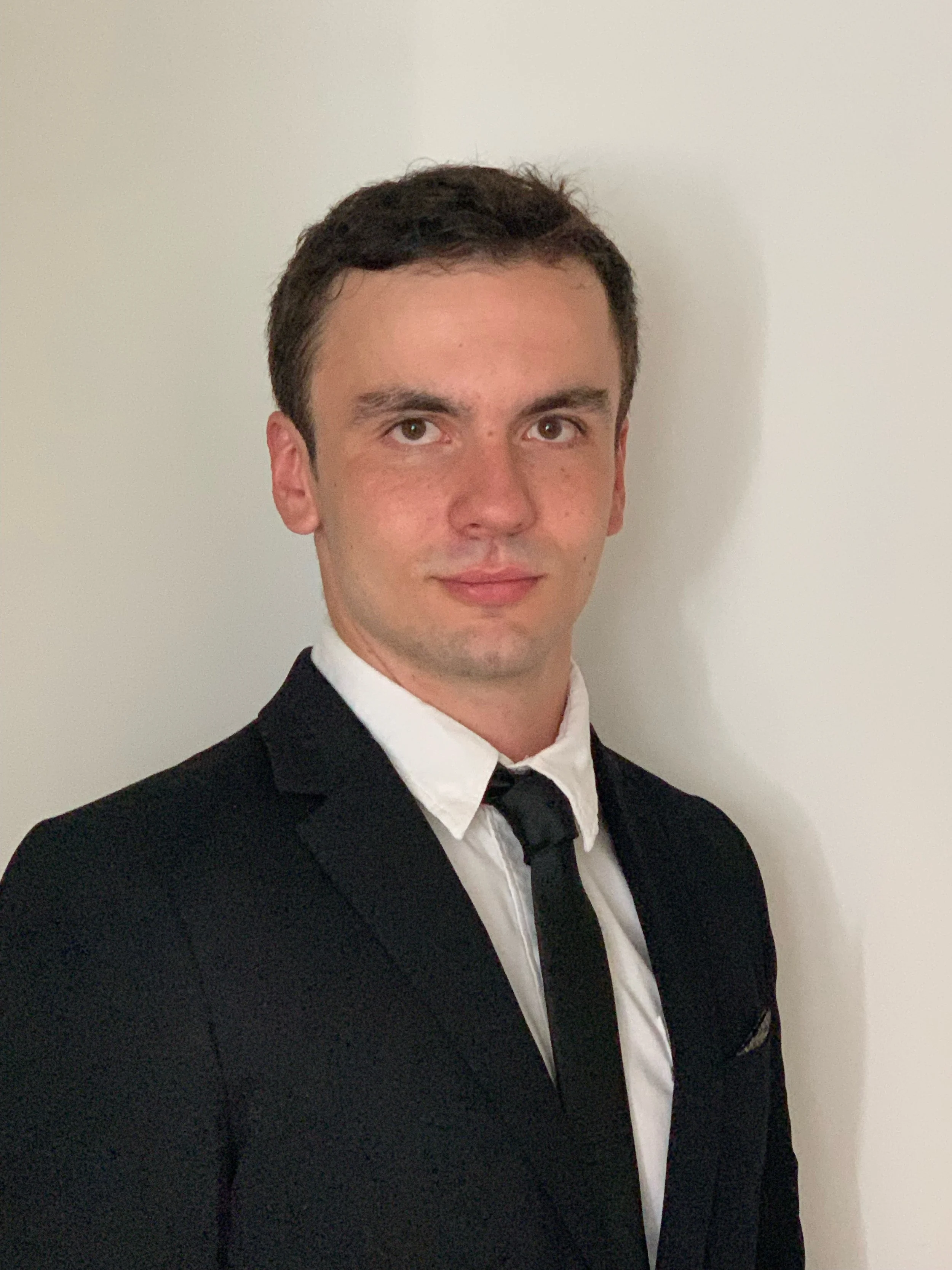 A man in a black suit, white shirt, and black tie standing against a white wall. Leanstock Partners CEO, focusing on inventory reduction, cash flow improvement, performance based model we only win when you do