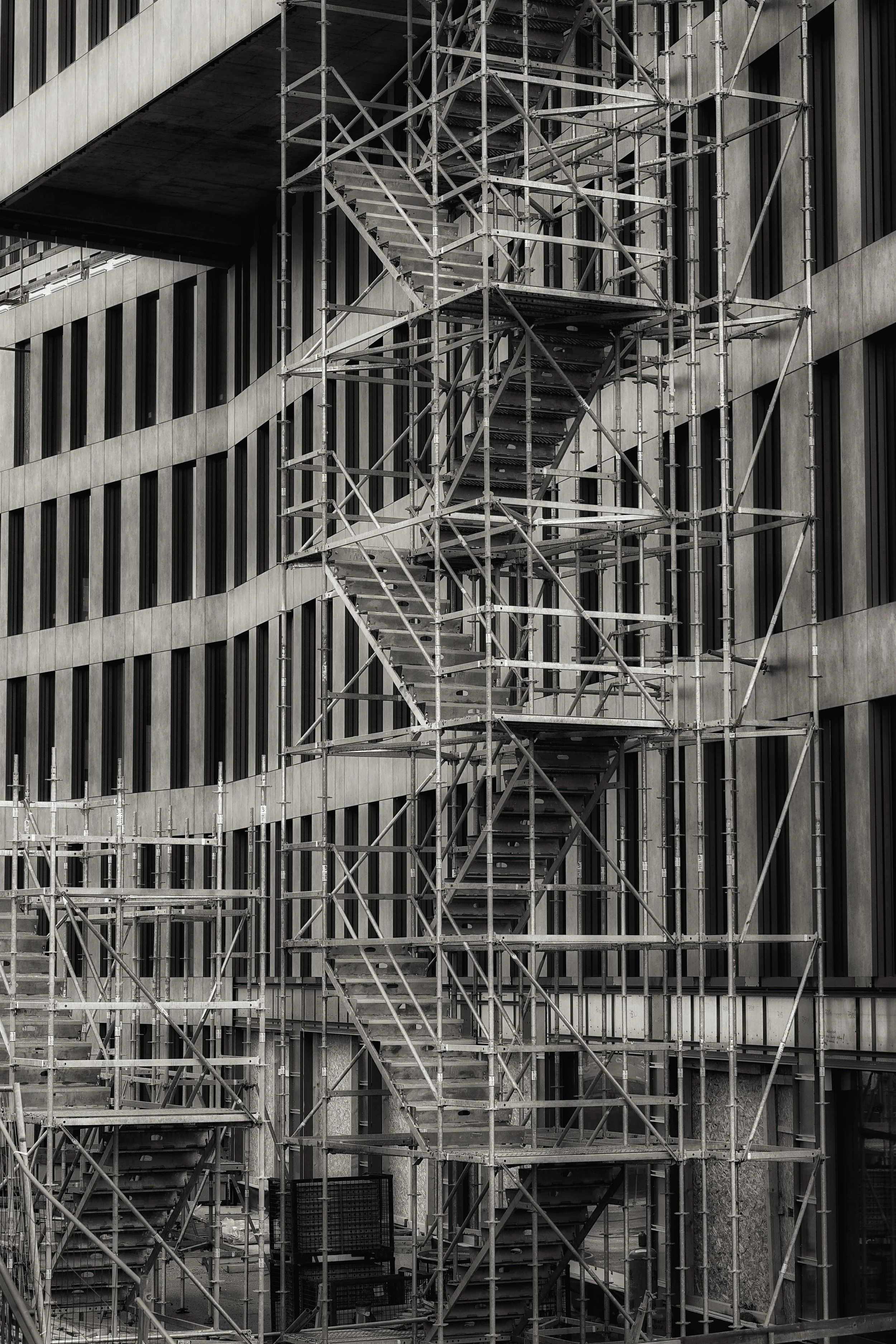 Escadas de obra de metal em um prédio de fachadas de vidro e concreto.