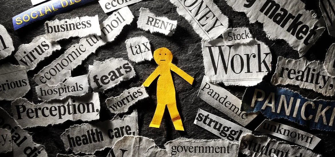A yellow paper figure surrounded by torn newspaper headlines with words like 'fear,' 'worries,' 'panic,' 'struggle,' and 'stress' indicating feelings of anxiety and distress.