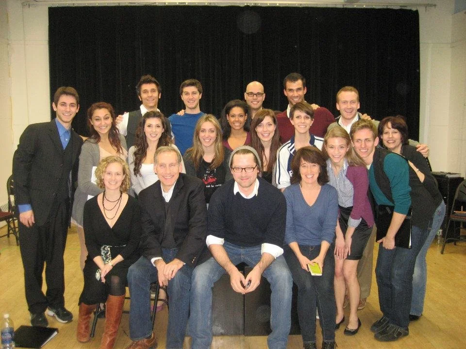 Group of people posing for a photo on a stage with a black curtain backdrop.
