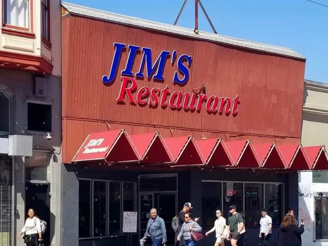 Exterior of Jim's By MLVS with a red awning and people walking by.