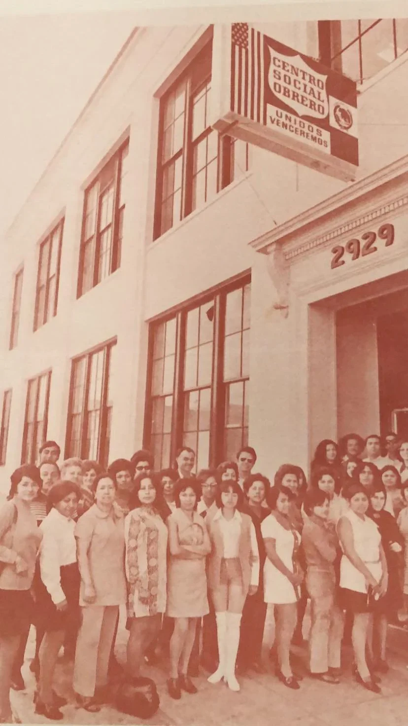 MLVS History: Group of women and men standing in front of a building with large windows and the number 2929 above the entrance, with a sign for the Central Social Obrera, Union S Voleremos, and an American flag.