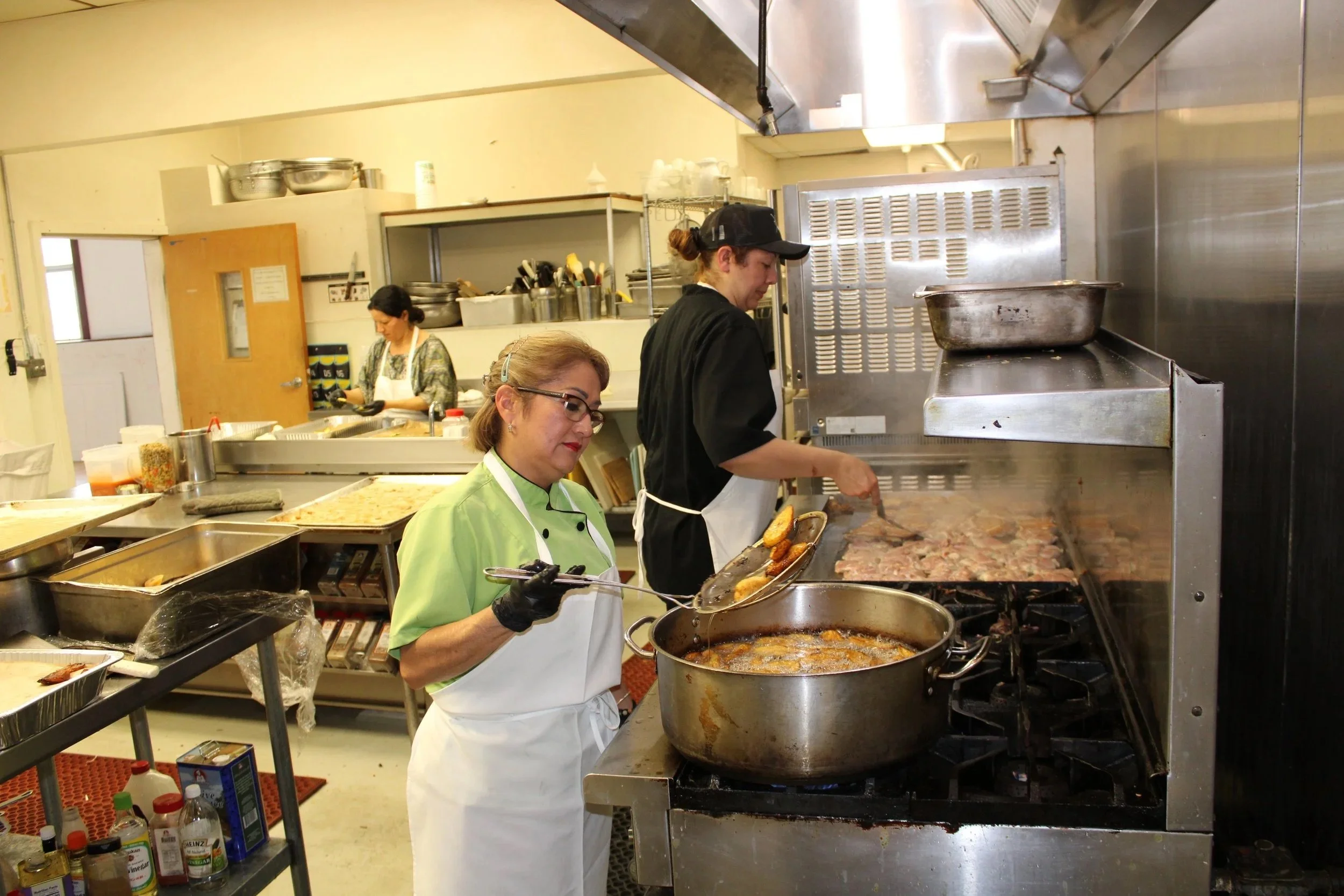 MLVS Culinary Program: Three women working in a commercial kitchen, preparing food on a stove.