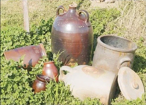 Various antique ceramic and clay jars and pots outdoors on grass.