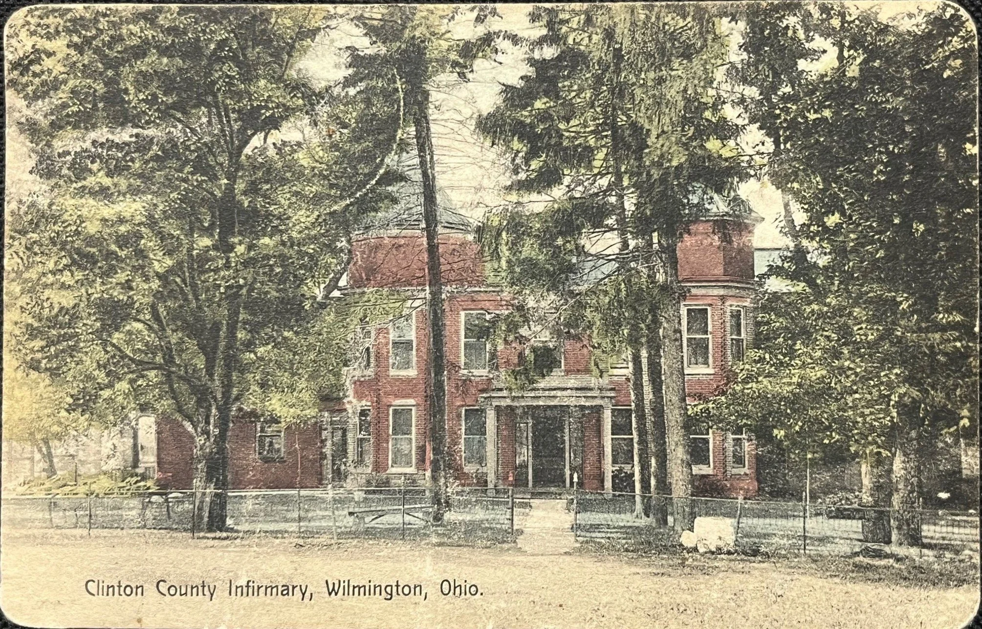 The original Clinton County Infirmary building on Fife Avenue, a two-story brick building with cupolas, on a hand-colored postcard from about 1909.