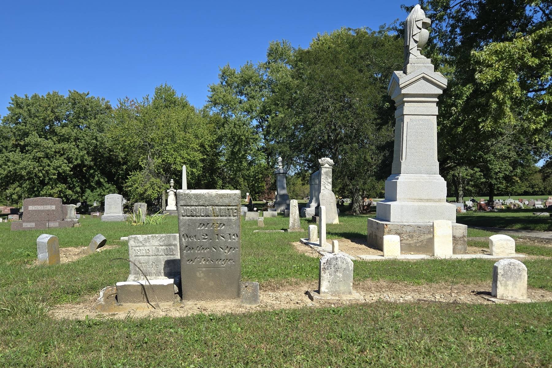 Joshua and Eleanor White's stones among older markers in Sabina Cemetery on a sunny day.