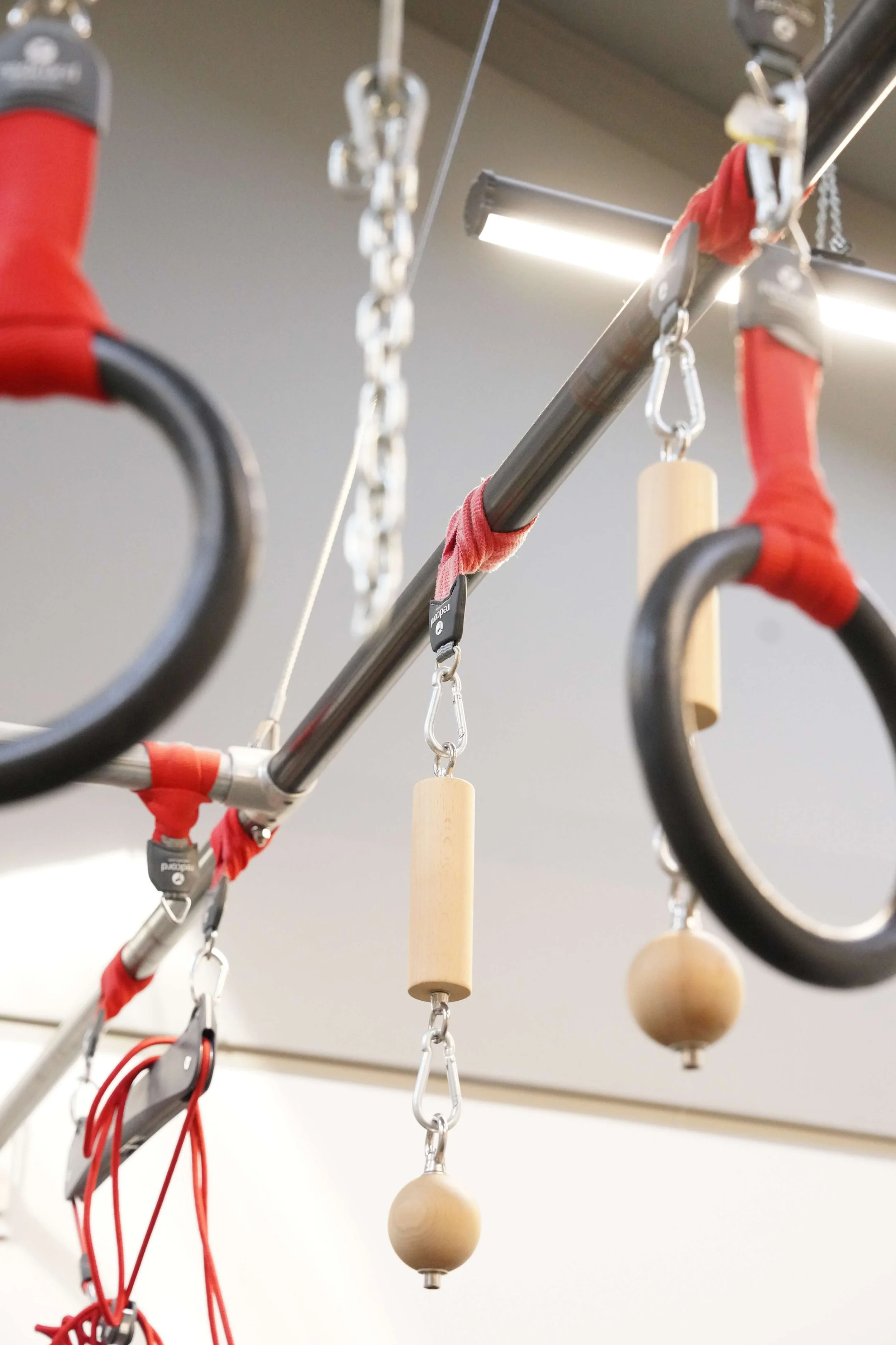 Gymnastic rings and accessories hanging from a metal rod in a fitness or gymnastics studio.