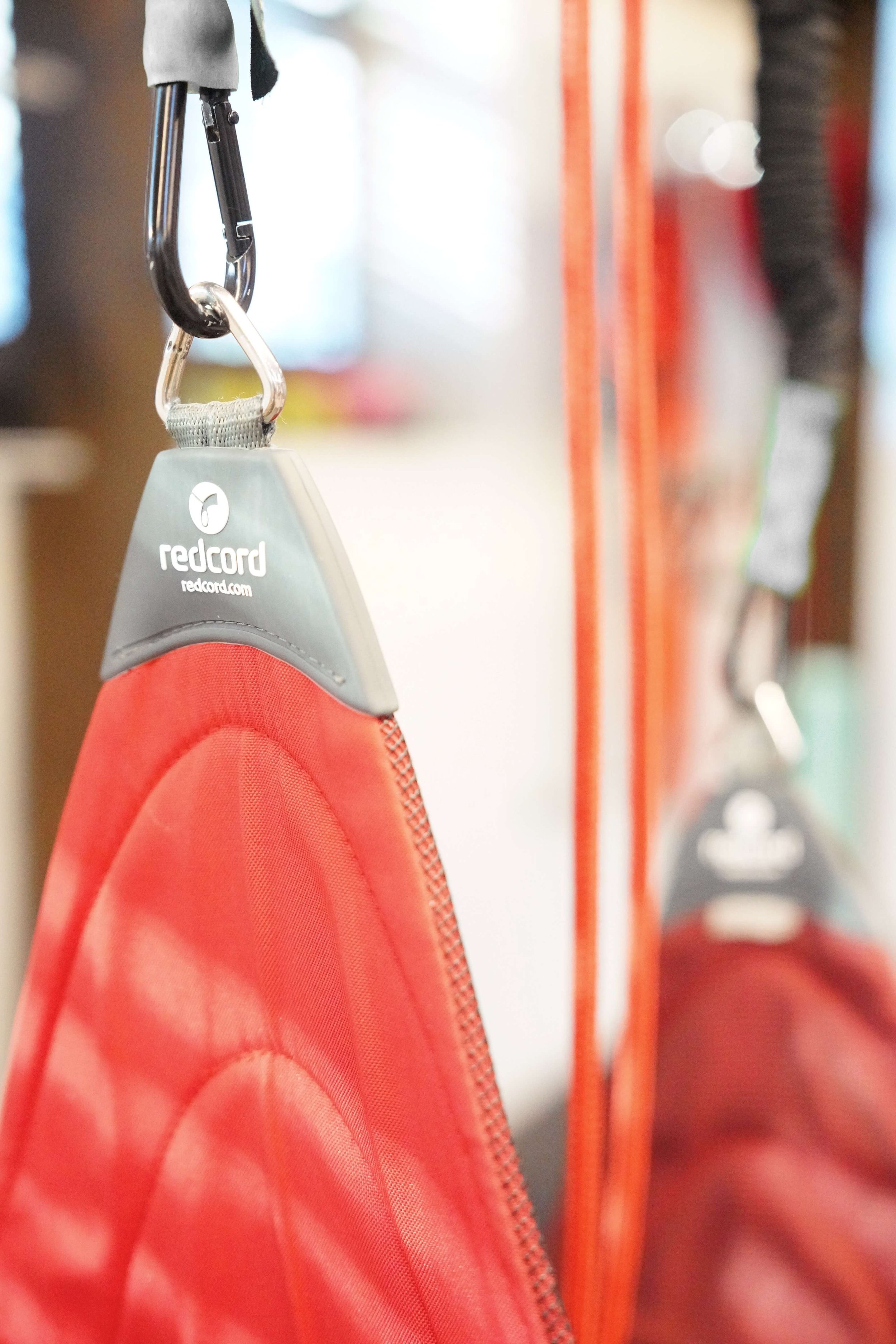 Close-up of red rescue flotation device with a gray plastic clip, hanging on a hook inside a rescue equipment storage area.