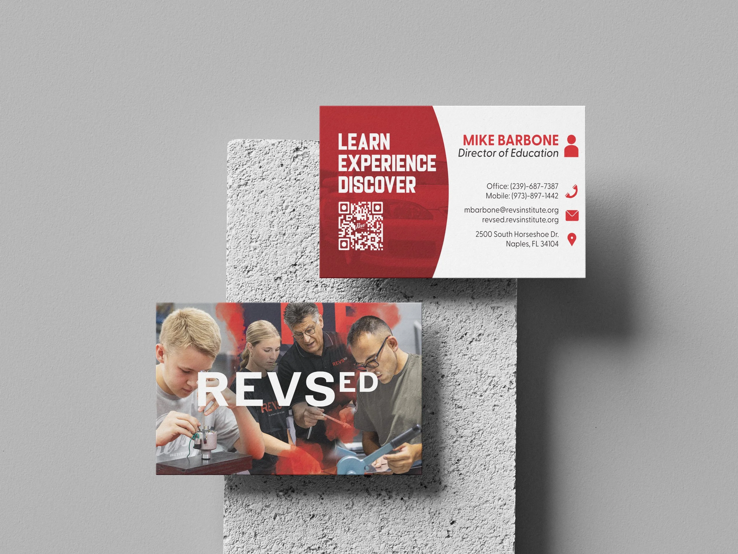 Business card with contact information and a photo of students and a teacher working on a science project with the word 'REVS' overlaid.