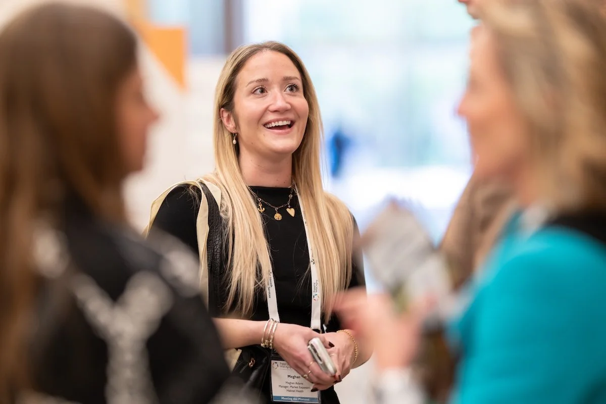 Man in a dark suit and glasses giving a presentation to an audience in a conference room.