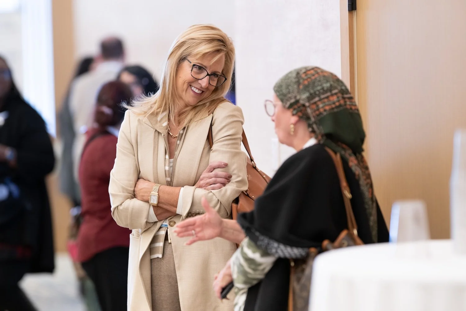 A woman with glasses and blonde hair giving a presentation or speech, holding a microphone.