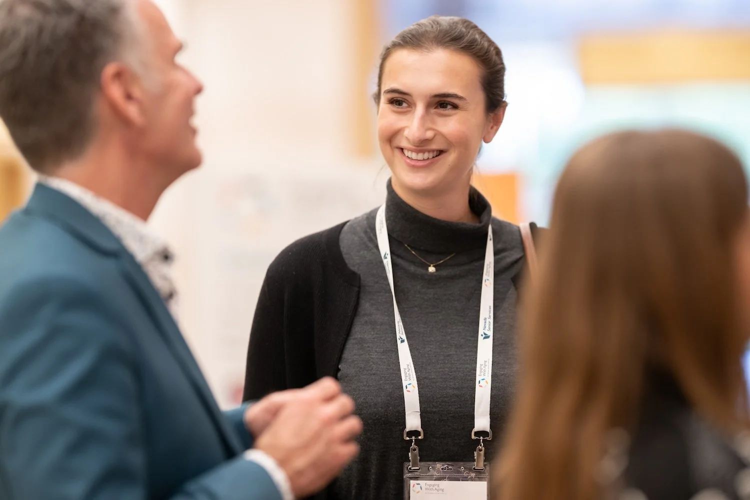Three women engaging in a conversation at a social event, each holding a disposable coffee cup.