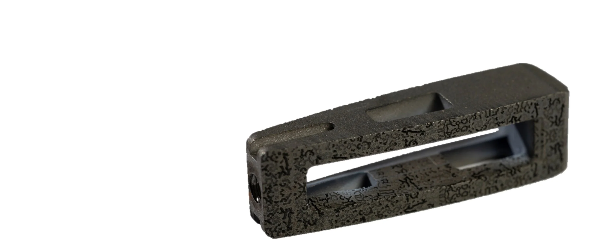 lumbar implant with biobraille with rectangular opening, resting on a white surface, casting shadows.