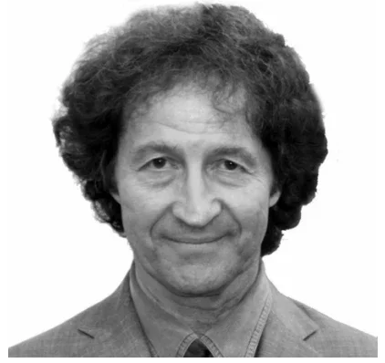 Black and white portrait of a man with curly hair, wearing a collared shirt and blazer.